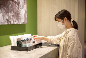 A person at a reception desk with a display of items in front of them.