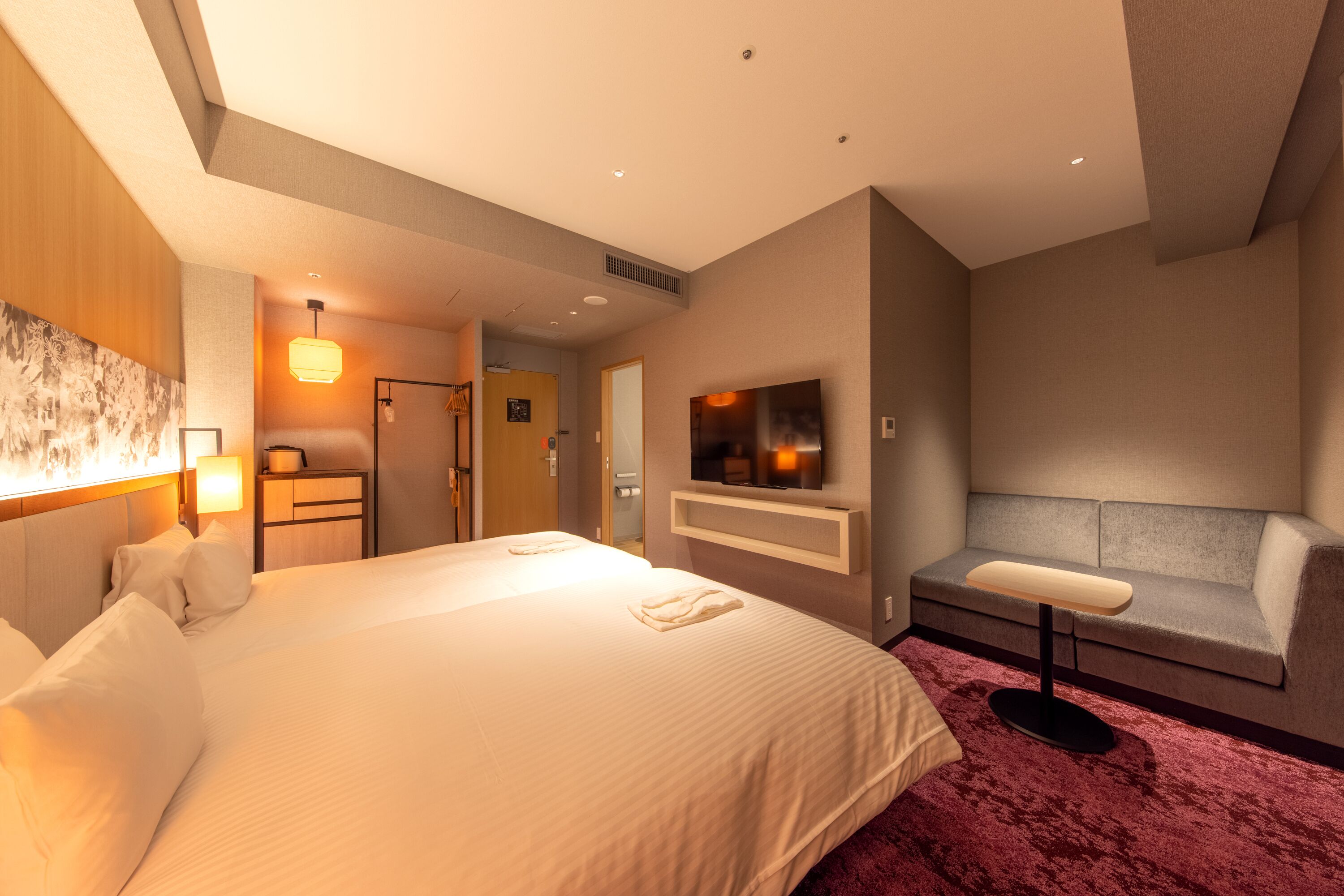 Una habitación de hotel moderna con una cama grande, un televisor, un sofá y un escritorio.