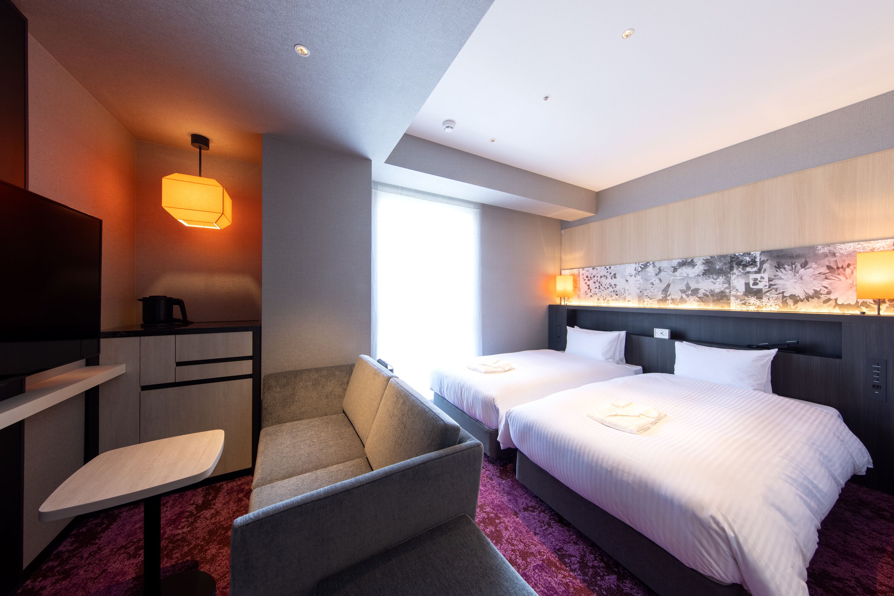 A hotel room with a bed, a desk, a chair, and a TV.