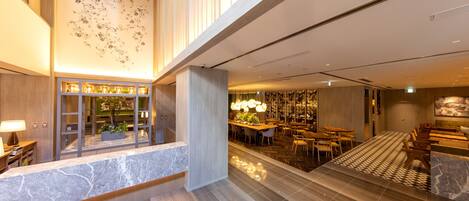 A modern hotel lobby with a reception desk, seating area, and a decorative wall.
