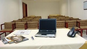 A conference room with a laptop, a telephone, and some papers on a table. - Maxim Plaza Hotel (Juiz de Fora)