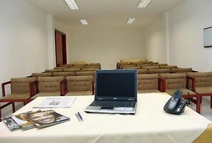 Sala de conferências com um laptop, um telefone e alguns papéis sobre uma mesa.