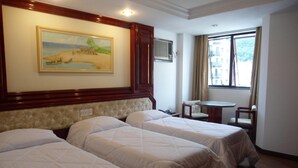 A hotel room with two beds, a painting on the wall, a window with a view, and a small table with a chair. - Maxim Plaza Hotel (Juiz de Fora)