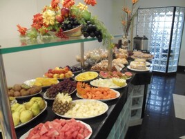 Buffet com diversas frutas, legumes e sobremesas.