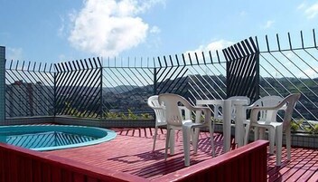 Uma piscina no terraço com vista para montanhas, cercada por uma grade de metal.