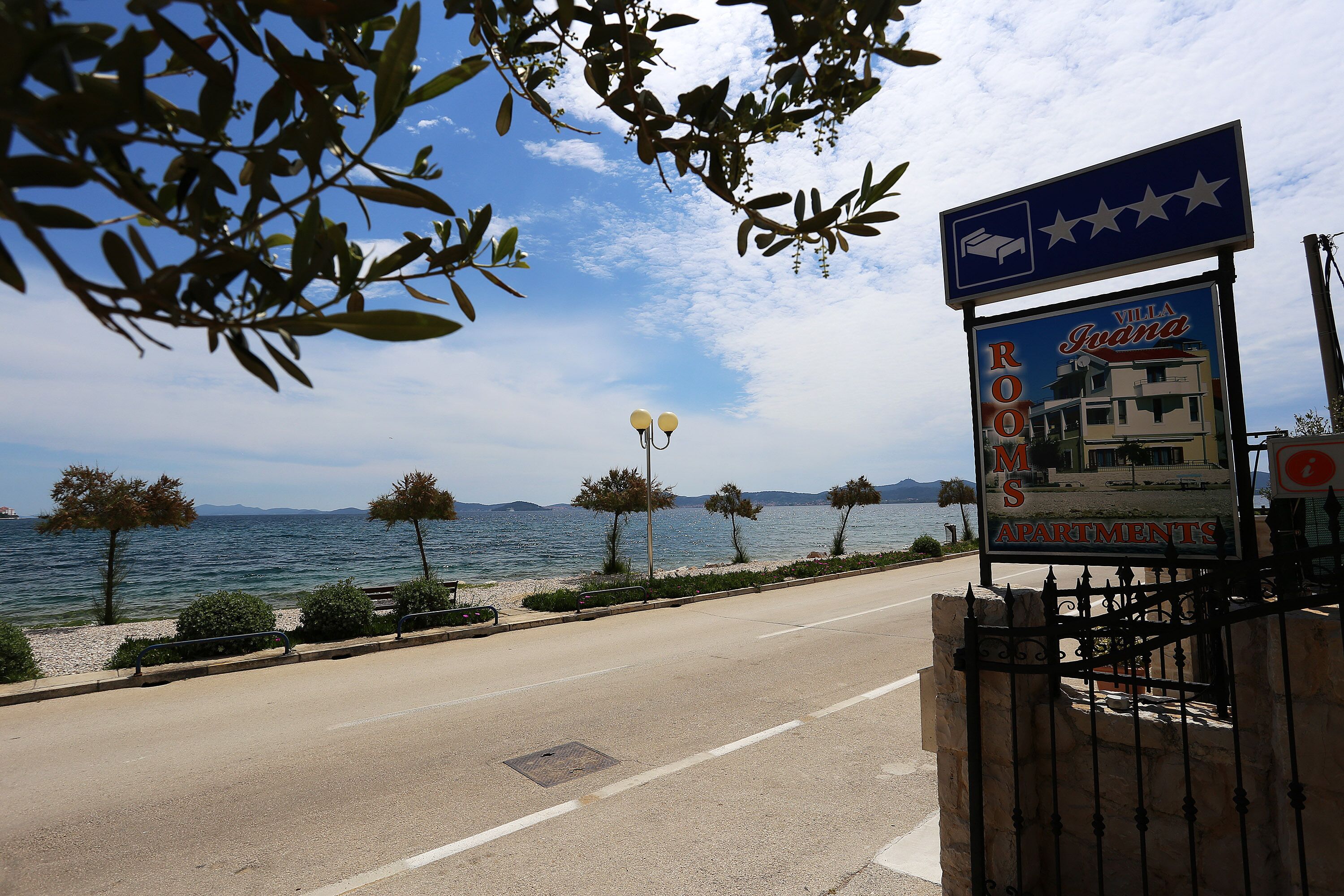 A signboard for Villa Guana with a view of the sea and mountains in the background.