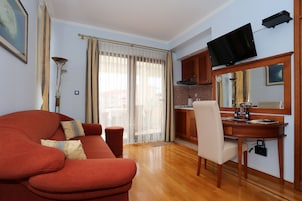 A living room with a red sofa, a wooden dining table, and a TV mounted above it.