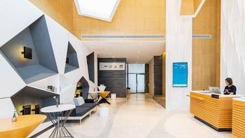 A modern hotel lobby with geometric seating, a reception desk, and a visible sign with Chinese characters.