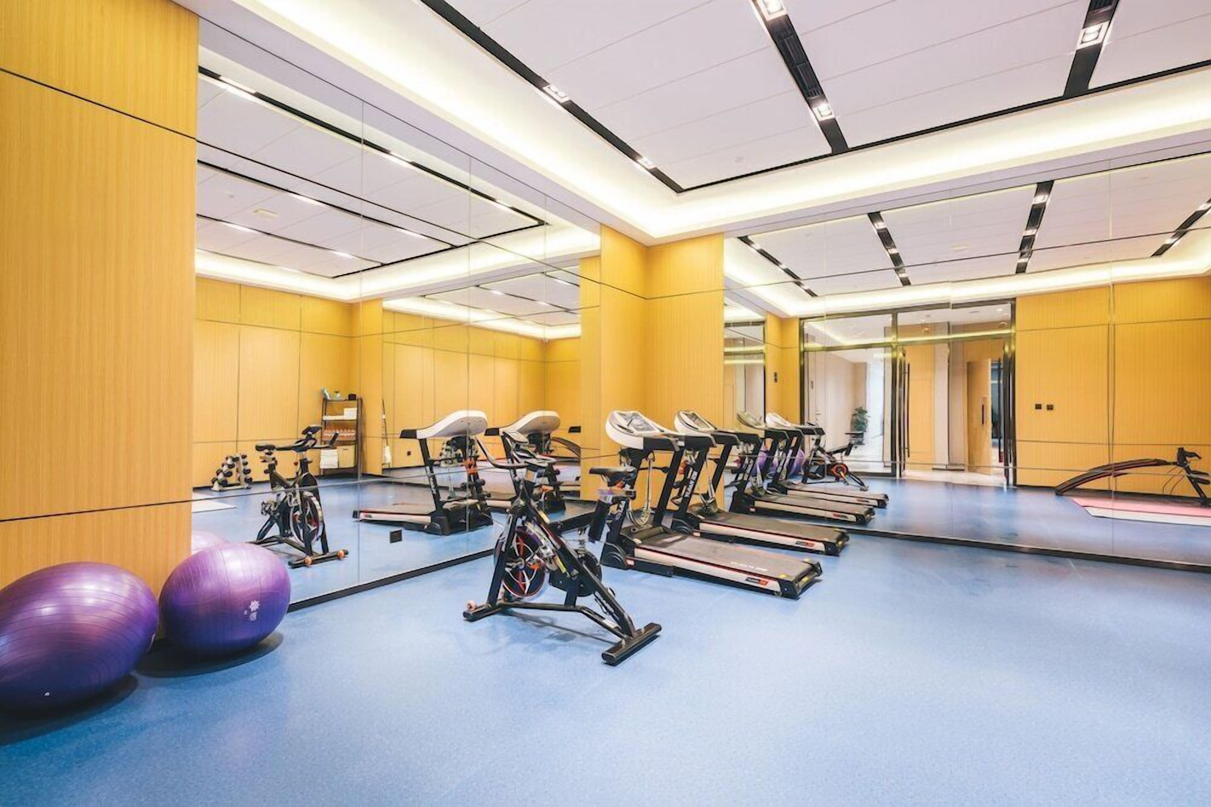 A gym with exercise equipment, a blue floor, and mirrored walls.