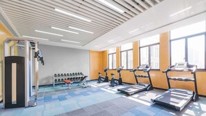 Ein Fitnessraum mit Laufbändern, Crosstrainern und einem Gewichtsständer.