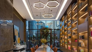 A modern library interior with a marble floor, hexagonal ceiling lights, and bookshelves. - Atour Hotel (Shenzhen)