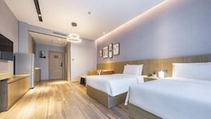 A hotel room with two beds, a wooden floor, a kitchenette, and a bathroom visible through an open door. - Atour Hotel (Shenzhen)