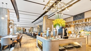 A modern cafe with a central bar area, seating arrangements, and a visible kitchen counter. - Atour Hotel (Shenzhen)
