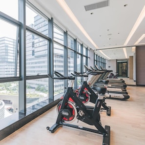 A gym with cardio machines and large windows offering a city view.