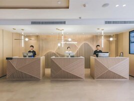 A reception area with three counters, each with a person seated behind. The counters have a geometric pattern.