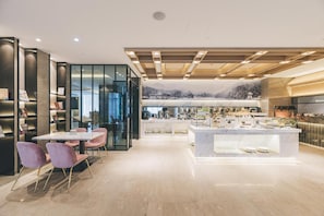 Eine moderne Hotelhalle mit Essbereich, einer Rezeption und Blick auf eine Berglandschaft.