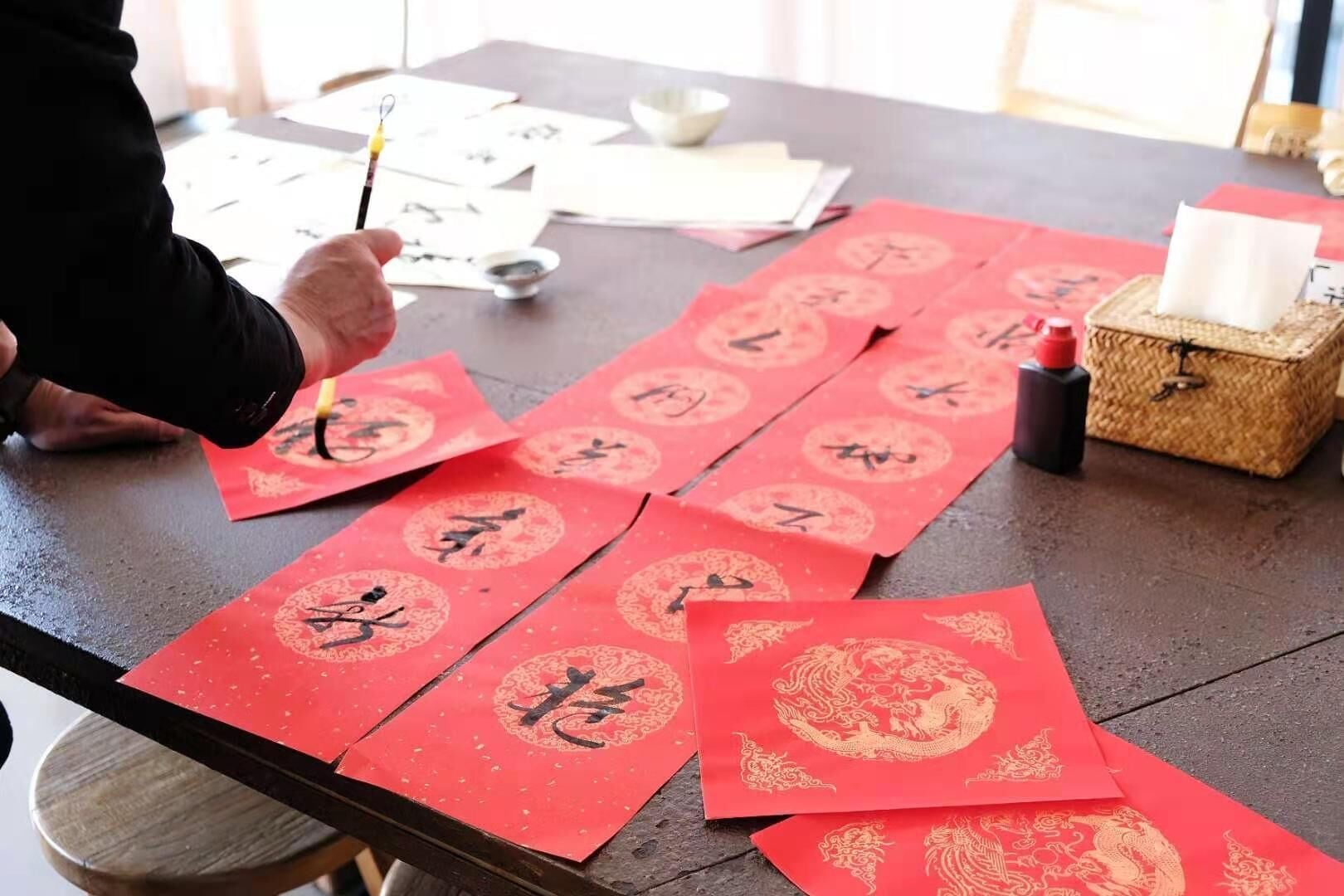 Uma mesa com envelopes vermelhos e materiais de caligrafia.