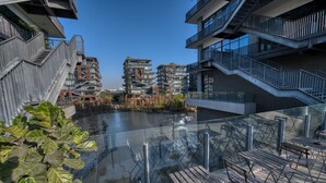 Un bâtiment moderne doté de nombreux balcons, d’une rambarde en verre et offrant une vue sur une rivière.