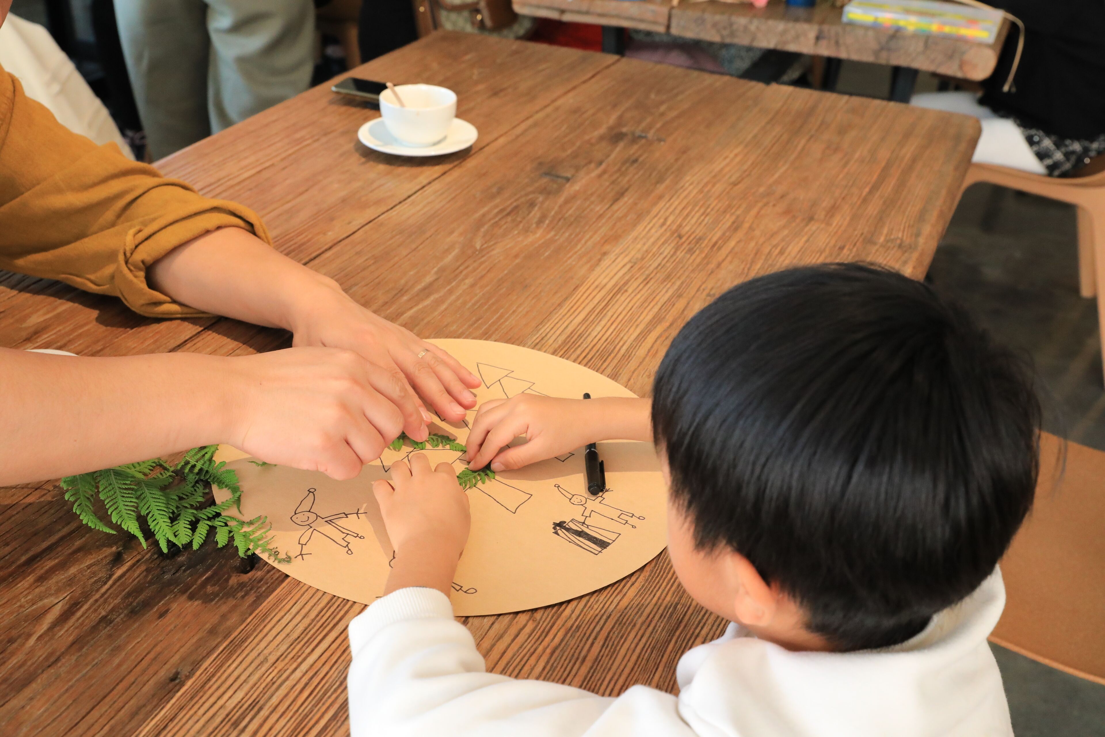 A wooden table with a circular paper mat featuring drawings.