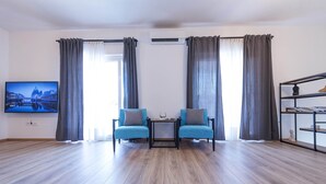 A modern living room with two blue armchairs, a small table, a flat-screen TV, and a bookshelf. - Holiday home Lana (Supetar)