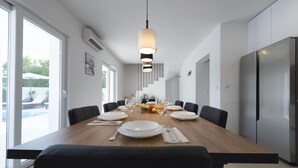 A modern dining room with a wooden table set for six, black chairs, and a hanging pendant light. - Holiday home Lana (Supetar)