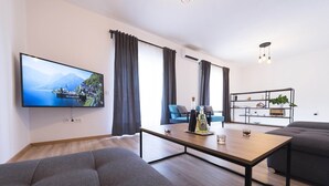 A modern living room with a flat-screen TV, grey sofas, a wooden coffee table, and a bookshelf. - Holiday home Lana (Supetar)