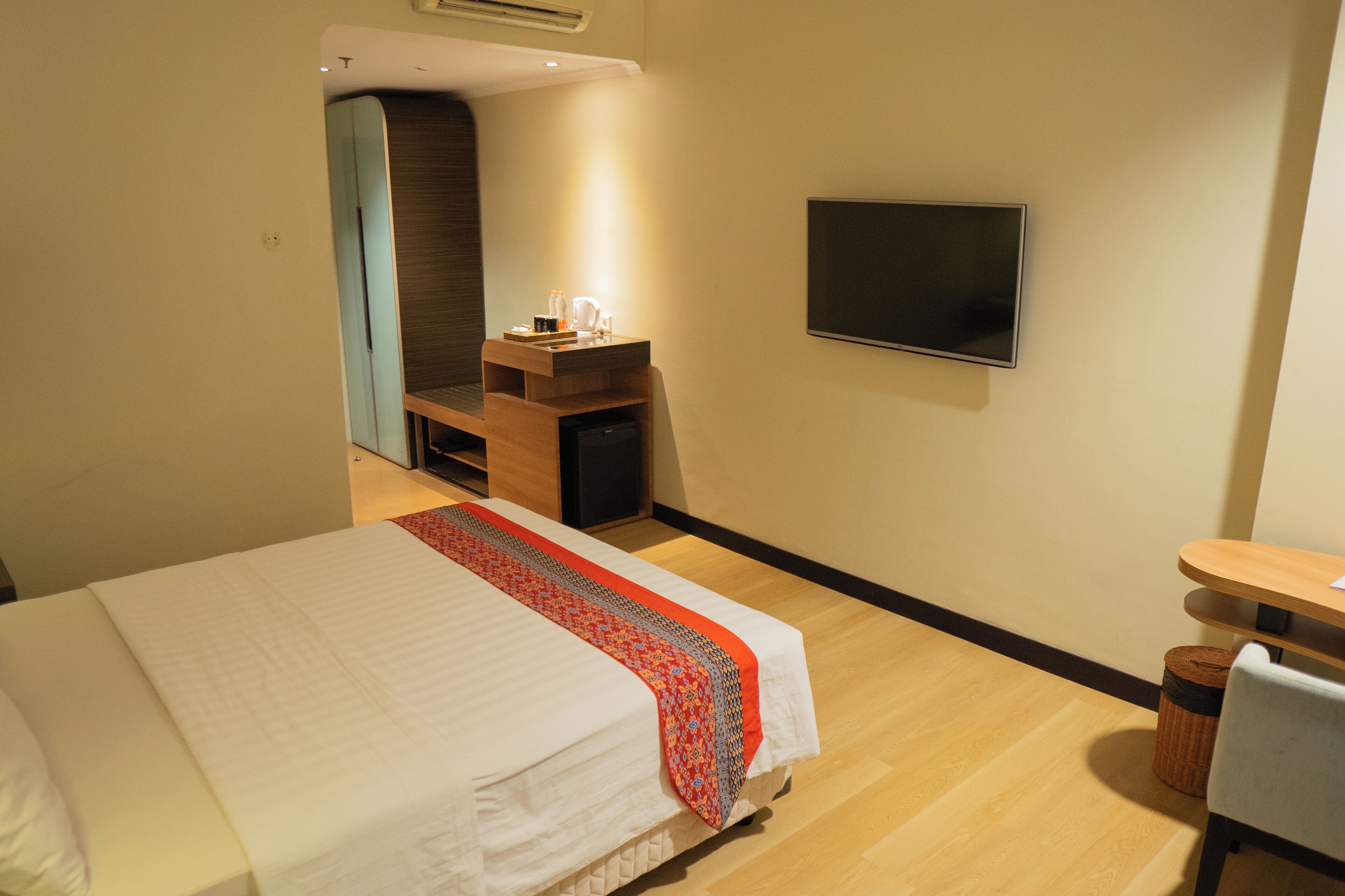 A hotel room with a bed, a desk, a TV, and a mirror.