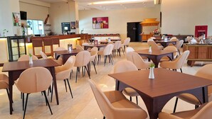 Un restaurant moderne doté de plusieurs tables et chaises, d’un bar et d’une cuisine située à l’arrière.