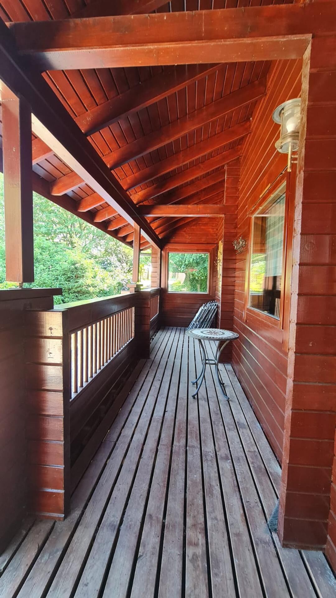 Eine Holzterrasse mit Geländer, Tisch und Bank.