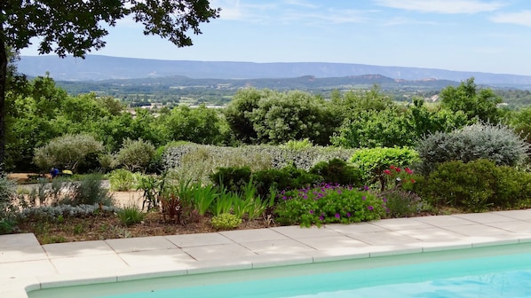 A pool with a view of a landscaped garden and distant mountains.