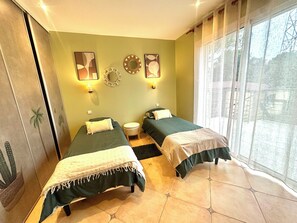 Une chambre avec deux lits, une grande fenêtre et des éléments de décoration fixés au mur.