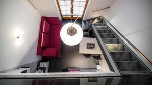A modern interior with a staircase, a red sofa, and a pendant light. - Golf Apartment (Moravske Toplice)