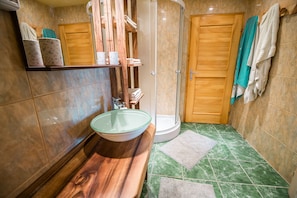 A bathroom with a wooden vanity, a glass sink, a shower, and a green tiled floor. - Apartment With Sauna pr' Geci (Brezice)