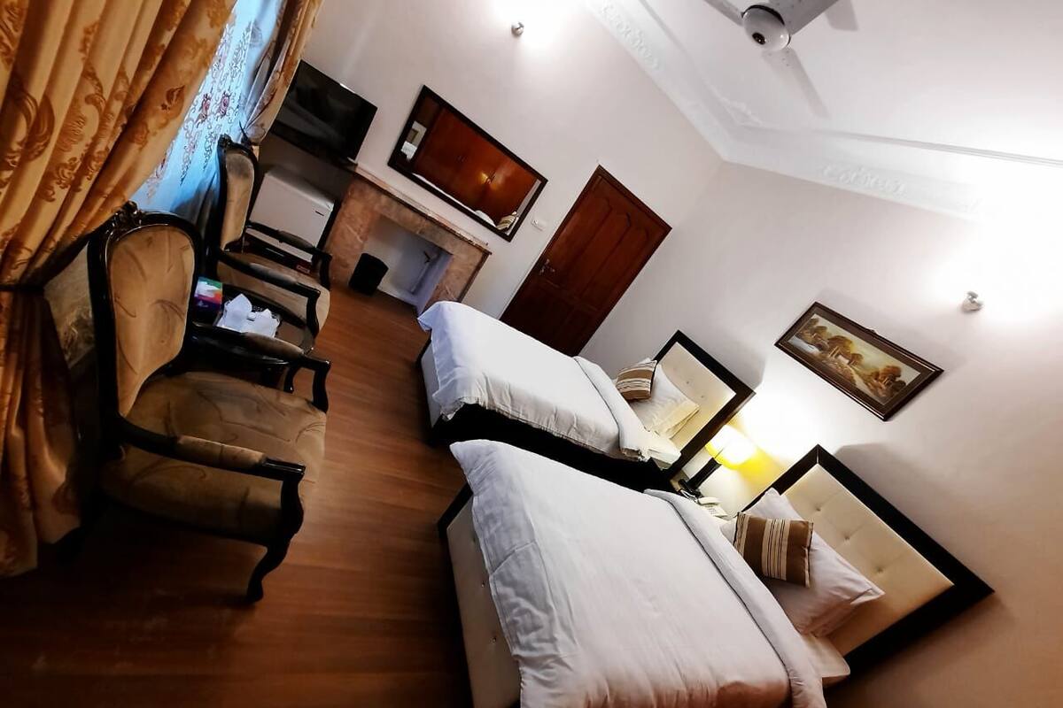 Una habitación de hotel con una cama, un escritorio, una silla, un televisor y una puerta.