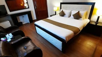 Habitació d'hotel amb un llit gran, escriptori amb cadira, televisió i un quadre a la paret.