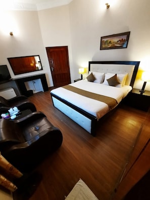A hotel room with a large bed, a desk with a chair, a television, and a painting on the wall. - Premier Inn Villa (Islamabad)