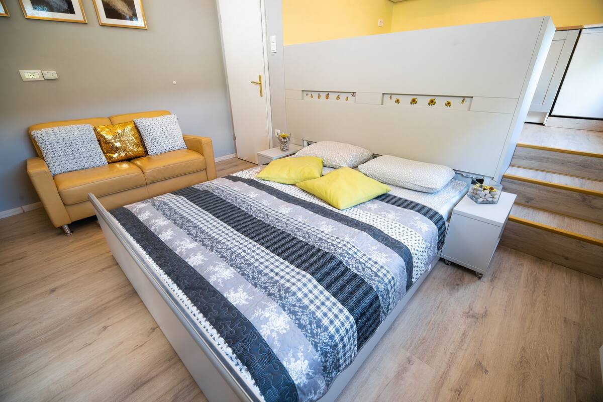 A modern bedroom with a large bed, a sofa, and a nightstand.