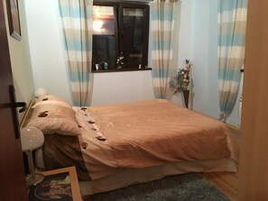 A bedroom with a bed, a window with curtains, a bedside table with a lamp, and a small plant. - Inviting 4-bed Villa in Dolishte (Aksakovo)