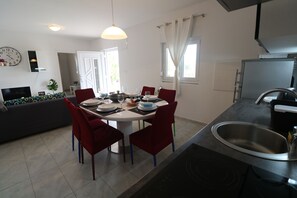 Une cuisine moderne avec un coin repas, un four encastré et une grande fenêtre avec des rideaux.