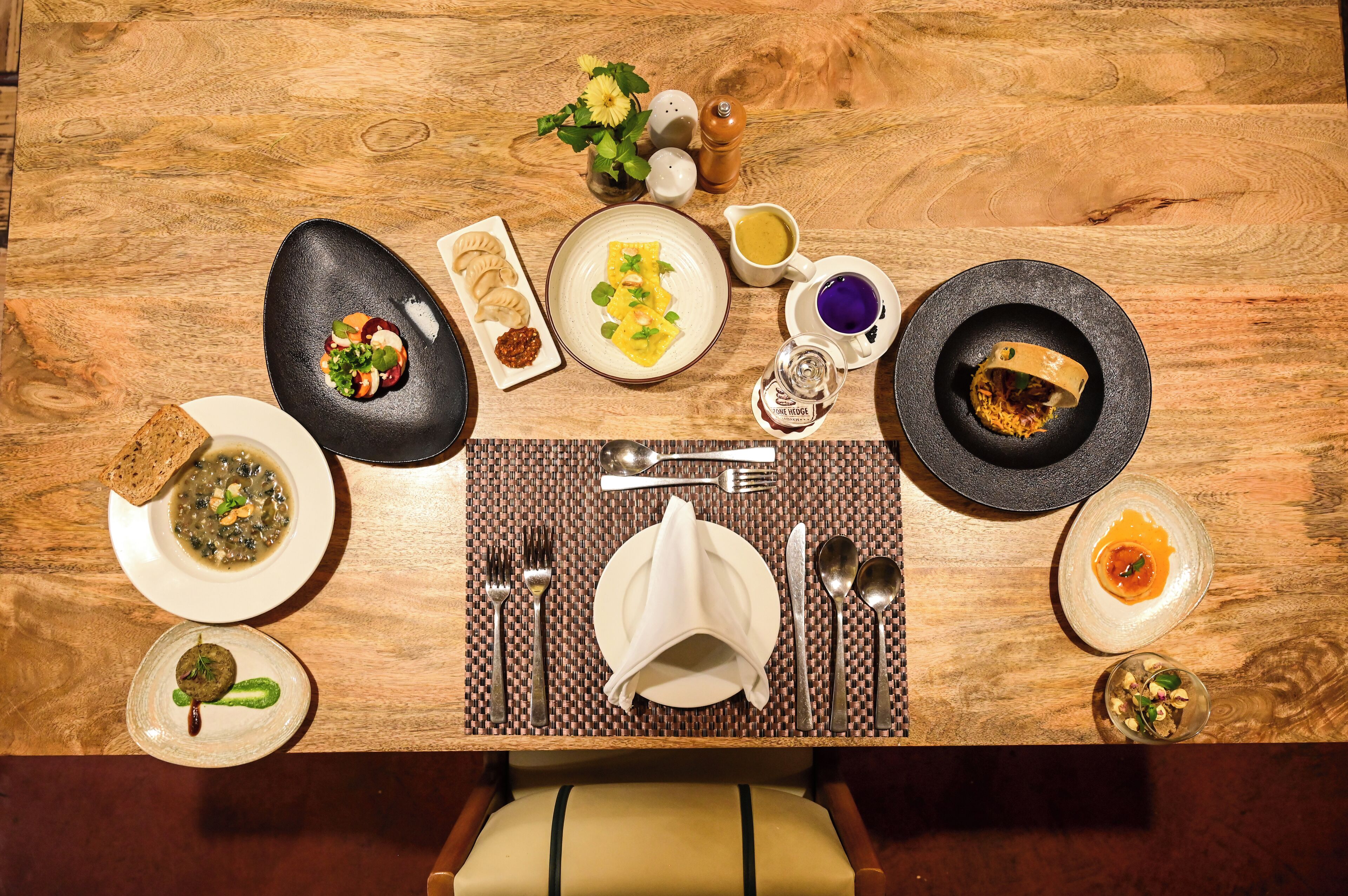 Una mesa de comedor dispuesta con varios platos, cubiertos y un florero.