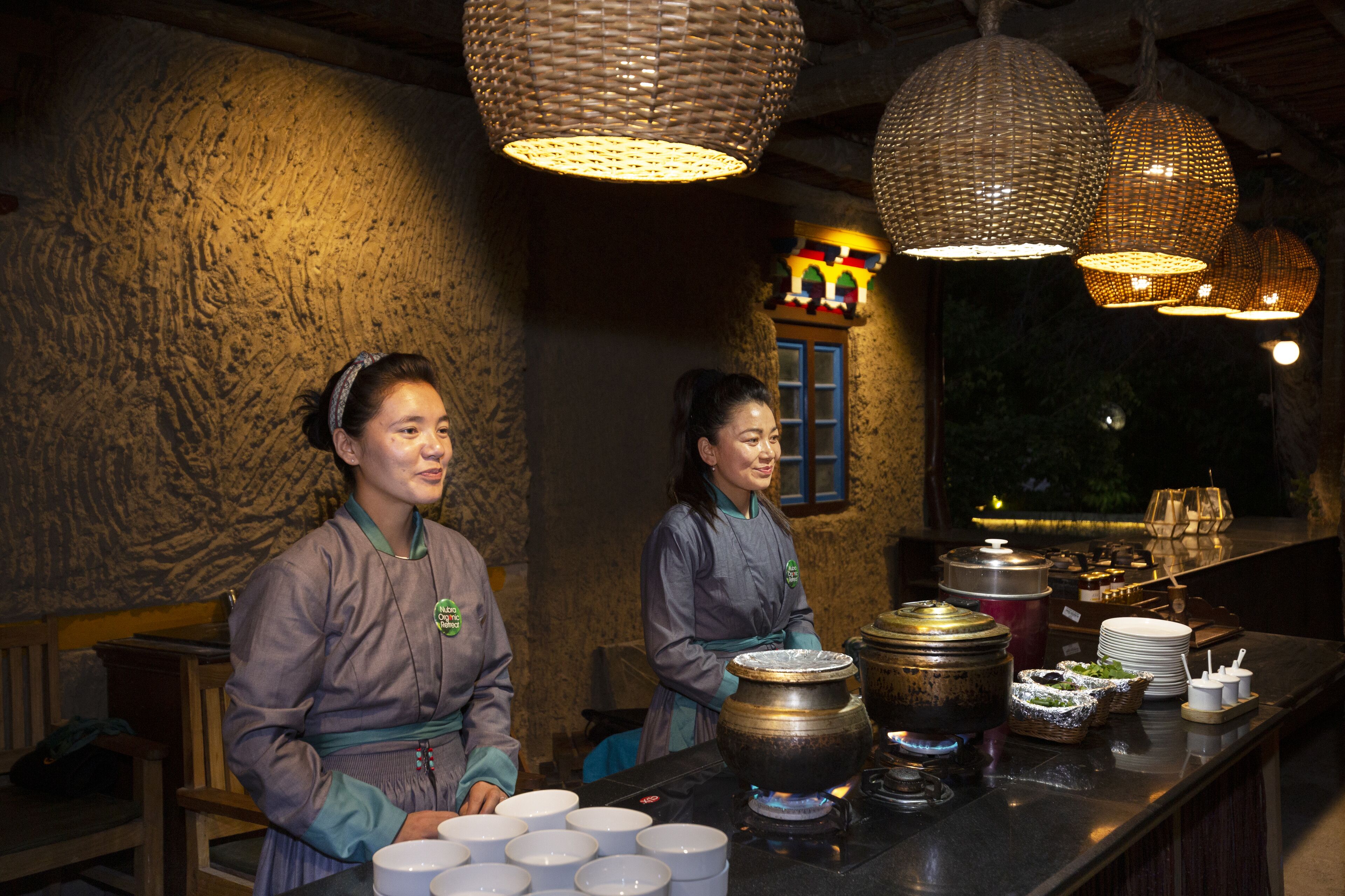 Un interior de restaurante con decoración tradicional, que incluye una pared de piedra y lámparas colgantes de tejido.