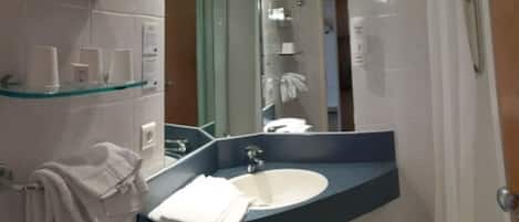 A modern bathroom with a curved sink, a glass shelf above the sink, and a towel rack to the left.