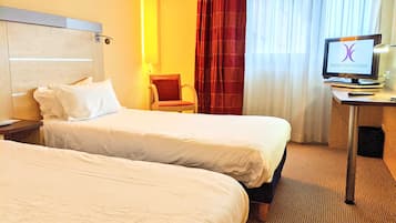 A hotel room with two beds, a desk with a computer, and a chair.