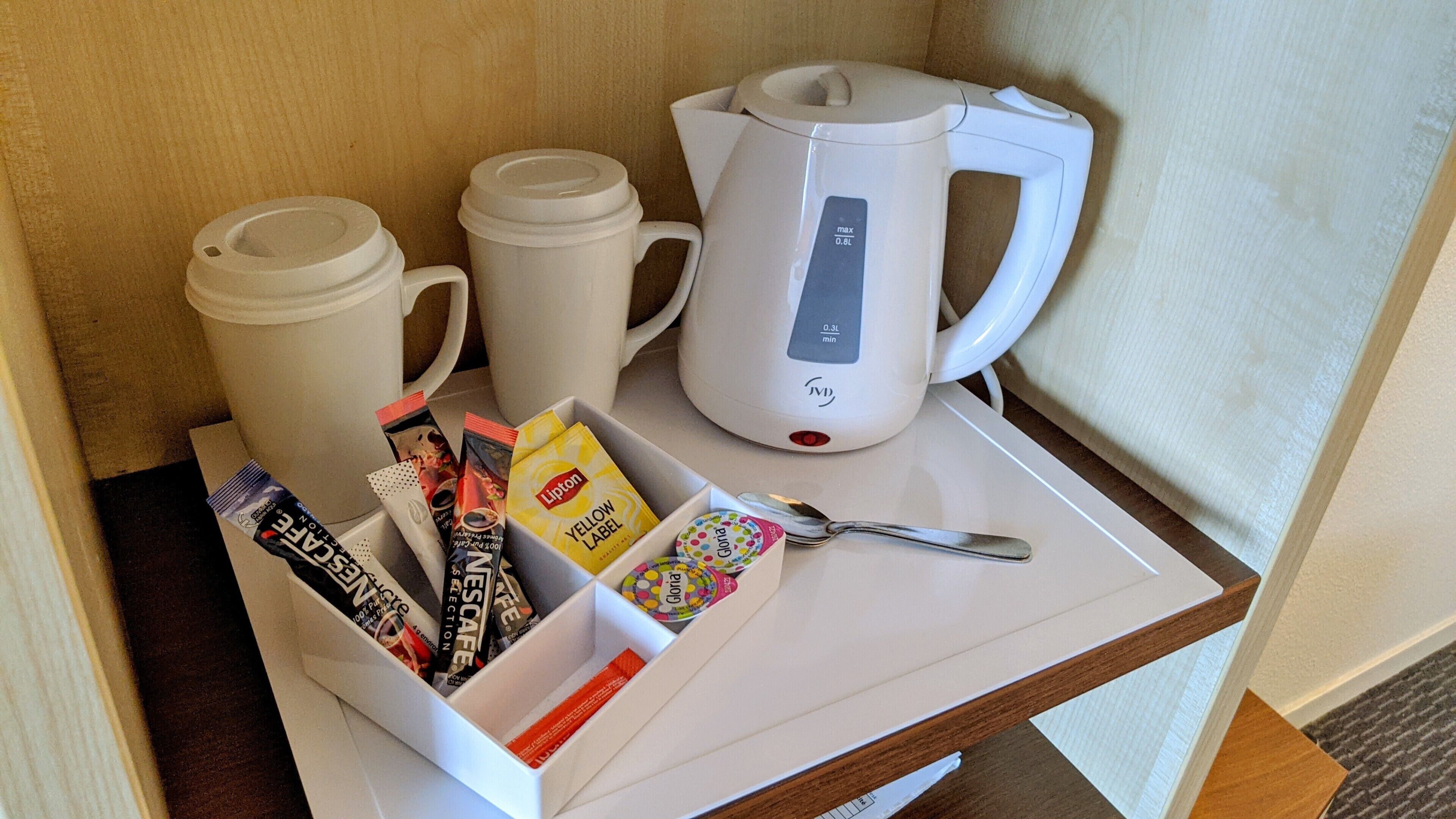 Un vassoio bianco con una macchina per il caffè, due tazze e una confezione di cialde per il caffè.