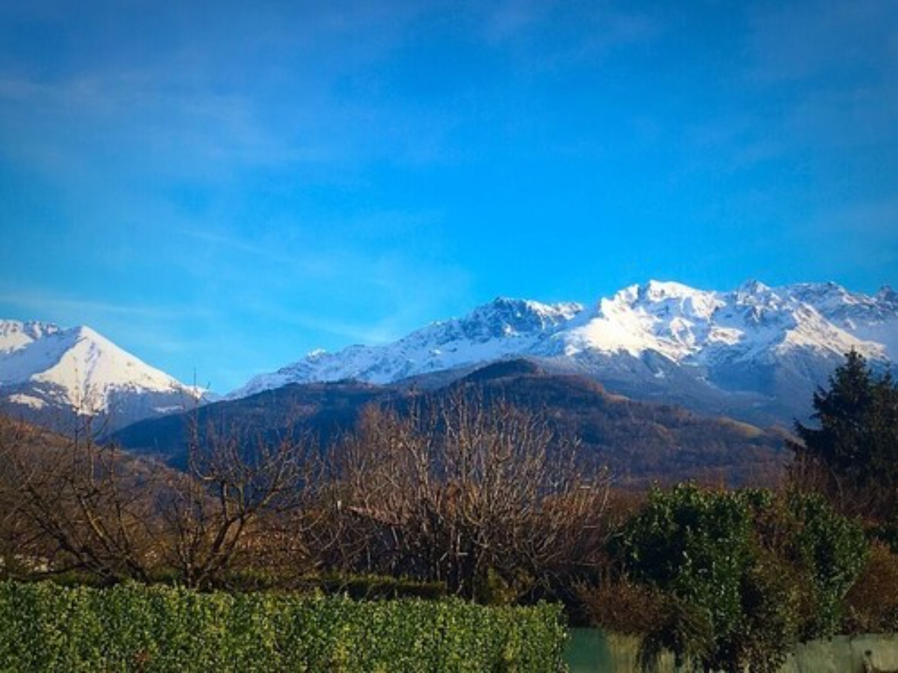Un paisaje montañoso con picos nevados y un cielo azul despejado.
