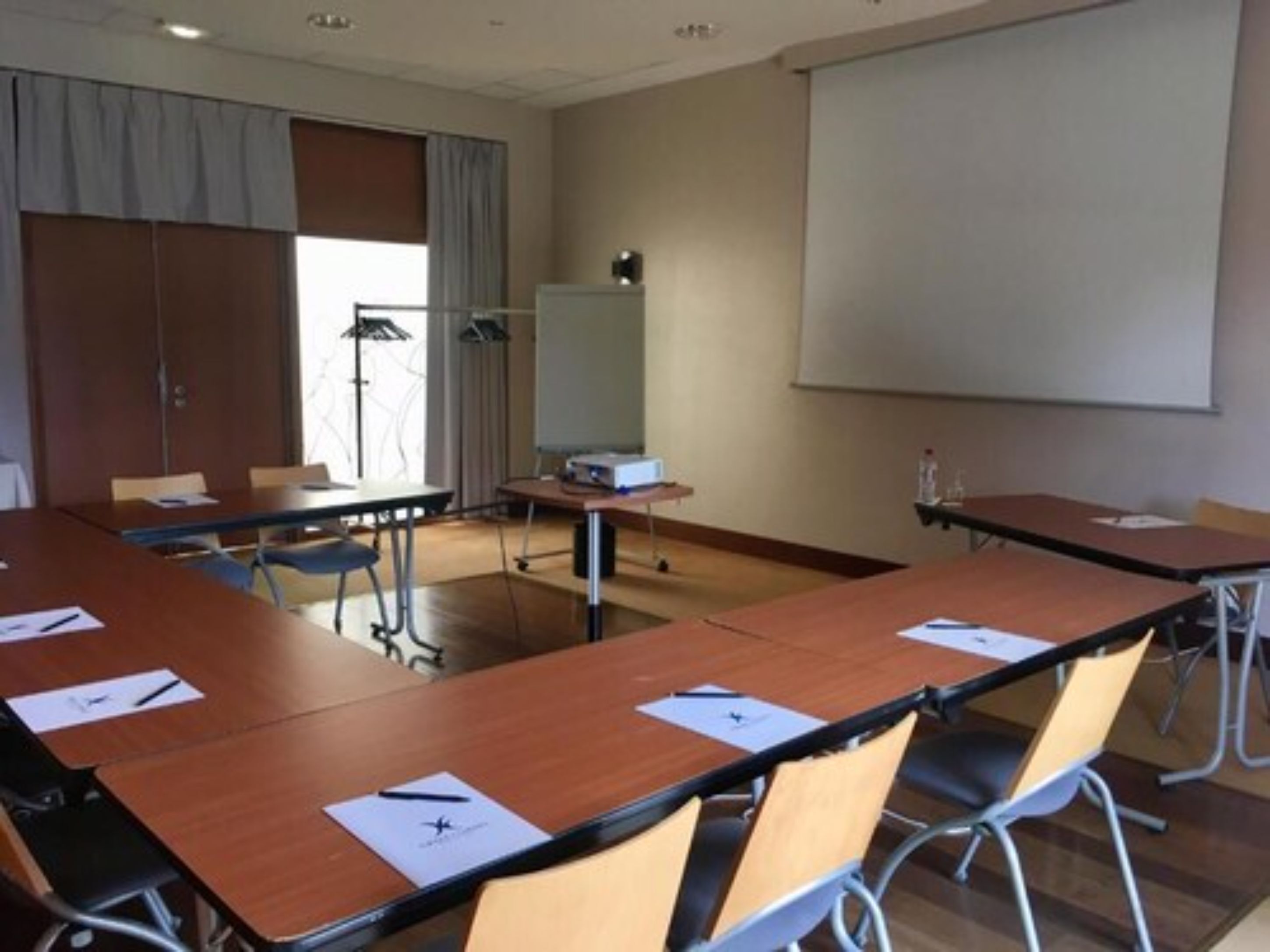 A conference room with a long table, chairs, a projector screen, and a whiteboard.