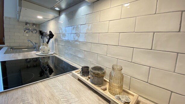 A modern kitchen with white subway tiles, a black countertop, and stainless steel appliances. - Experience Chiemsee, mountains & lakes - apartment for up to 4 people, 2 bedrooms, balcony (Marquartstein)