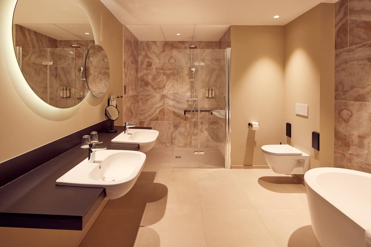 A modern bathroom with two sinks, a bathtub, and a glass-enclosed shower.