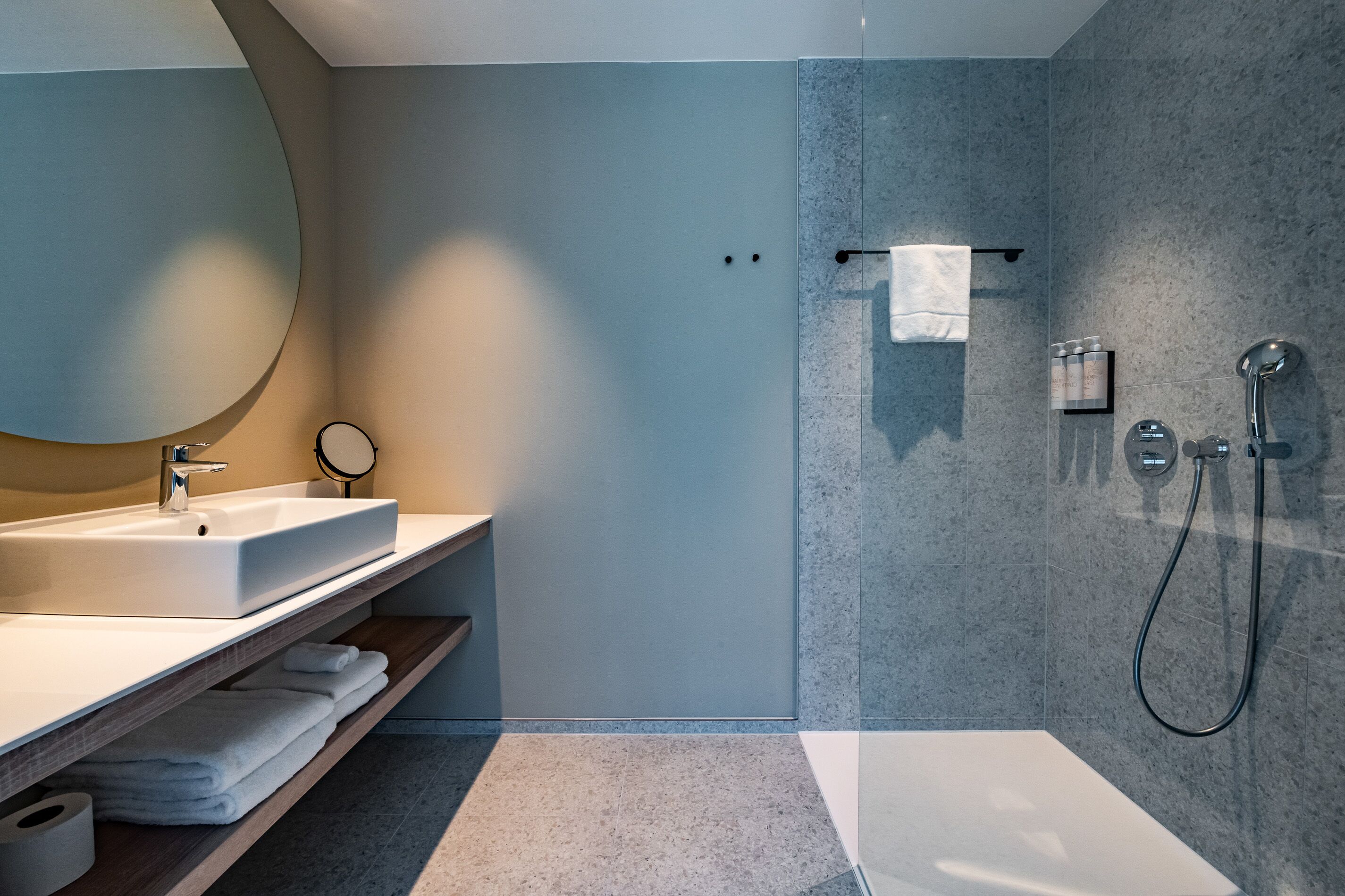 Un baño moderno con un espejo grande, un lavamanos, una ducha y una bañera.