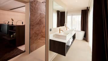 A modern bathroom with a large mirror, two sinks, and a bathtub.